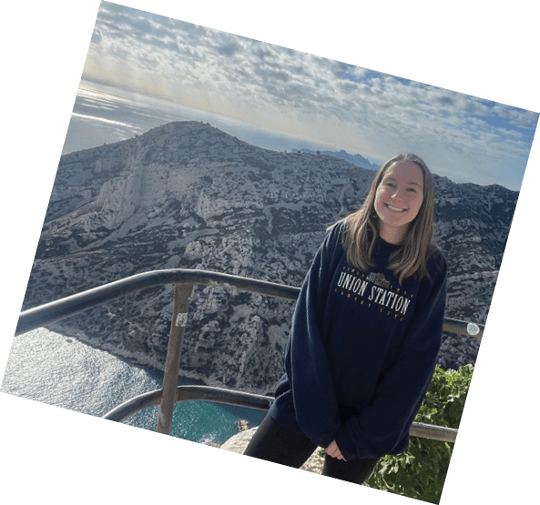A woman in a black sweatshirt is standing on a rocky cliff overlooking the ocean. AI generated content