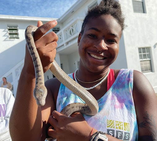 A woman is holding a snake in her arms, smiling. AI generated content