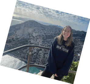 A woman in a black sweatshirt is standing on a rocky cliff overlooking the ocean. AI generated content