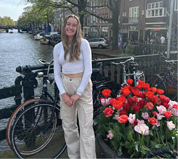 A woman in a white top and tan pants stands next to a bicycle. AI generated content