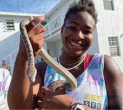 A woman is holding a snake in her arms, smiling. AI generated content