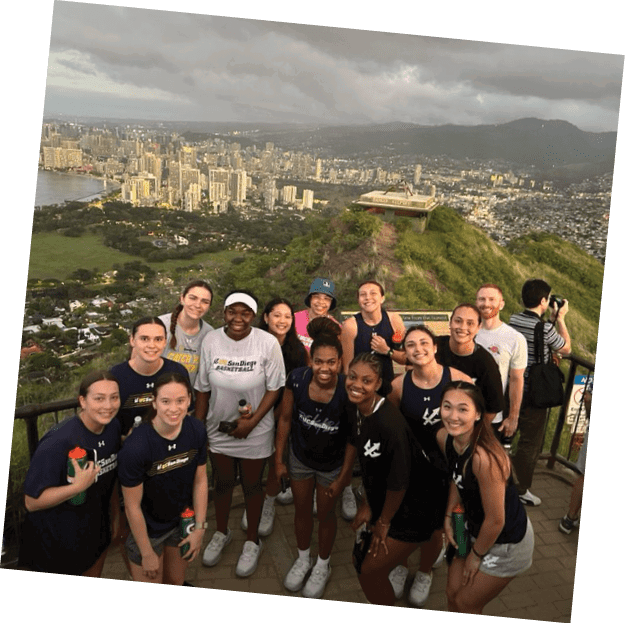 A group of women pose for a picture on a hill overlooking a city. AI generated content