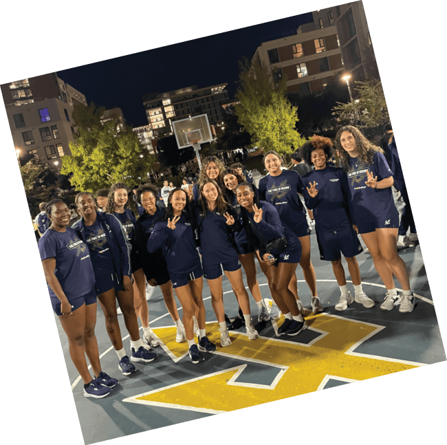 A group of women wearing blue shirts and black shorts pose for a picture on a basketball court. AI generated content