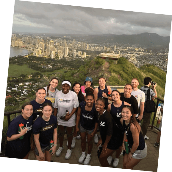 A group of women pose for a picture on a hill overlooking a city. AI generated content